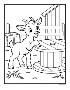 A baby goat climbing onto a big wooden spool next to a hay bale and the barn